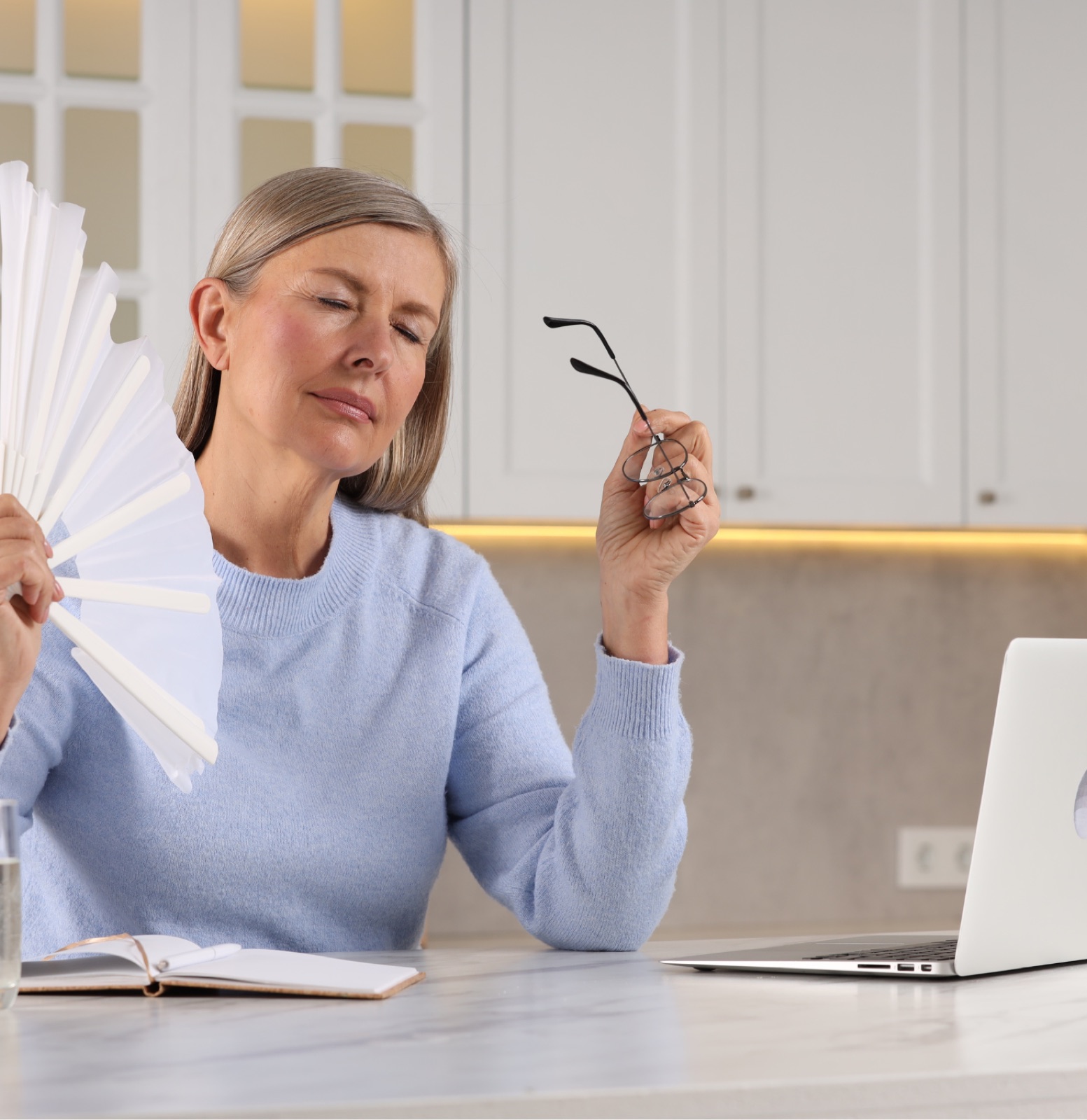 A woman cooling herself during a hot flush, menopause-related weight and metabolic change support